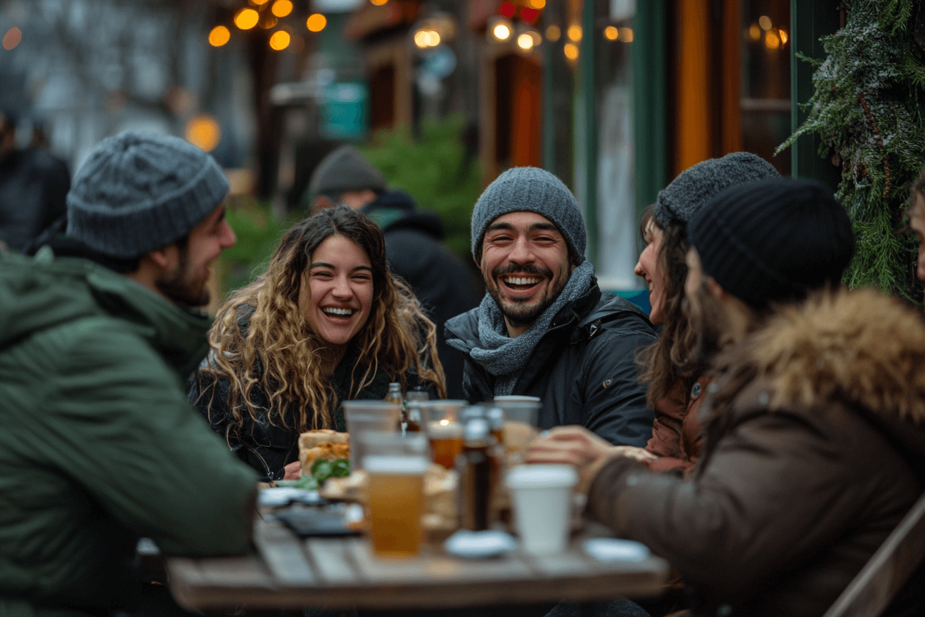 Friends gathered around a table outside, sharing food and laughter in a sunny setting.